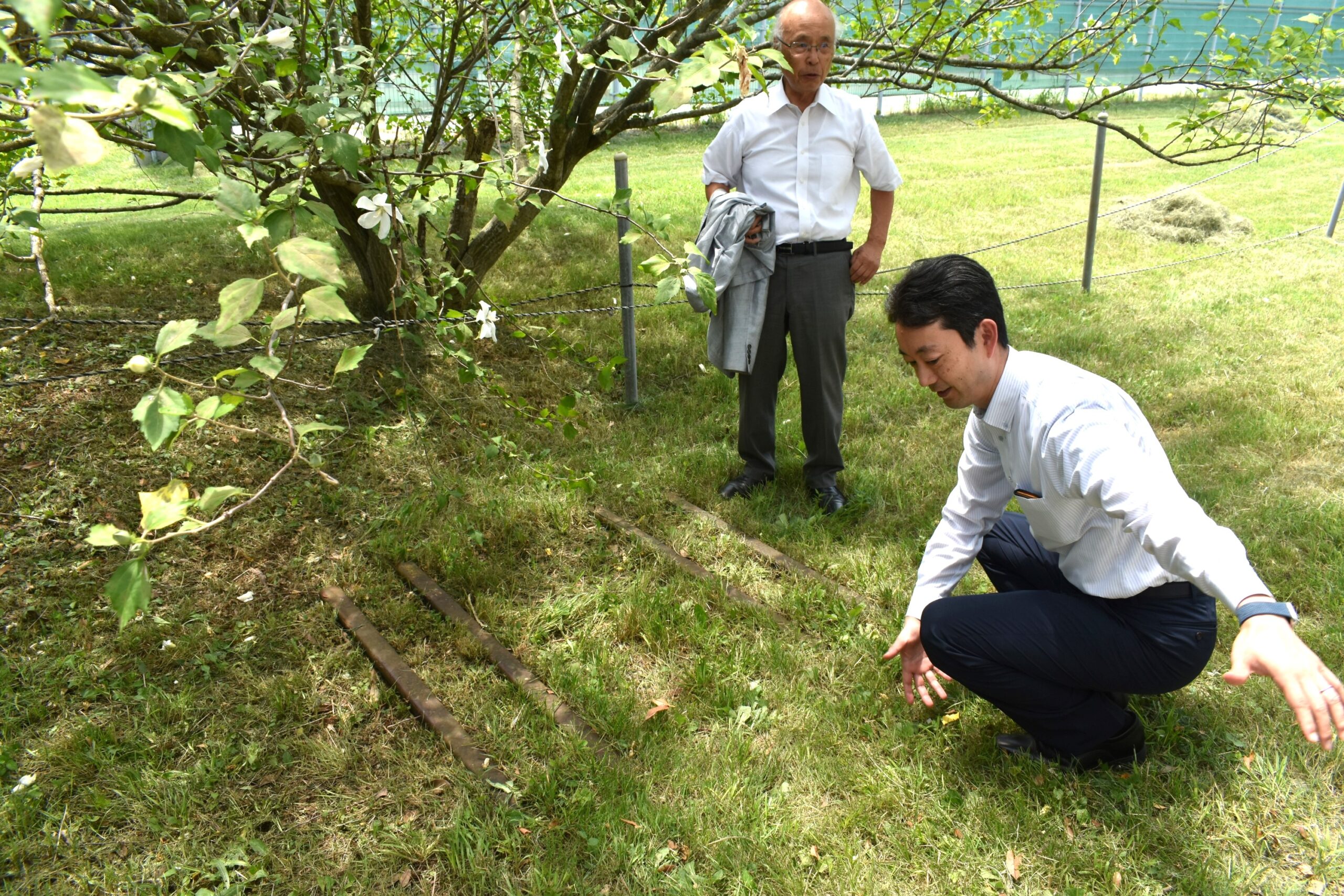 地面にある古いレールを見る二人の男性の画像